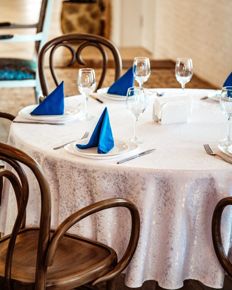 restaurant table with white lace table cloth and blue napkins